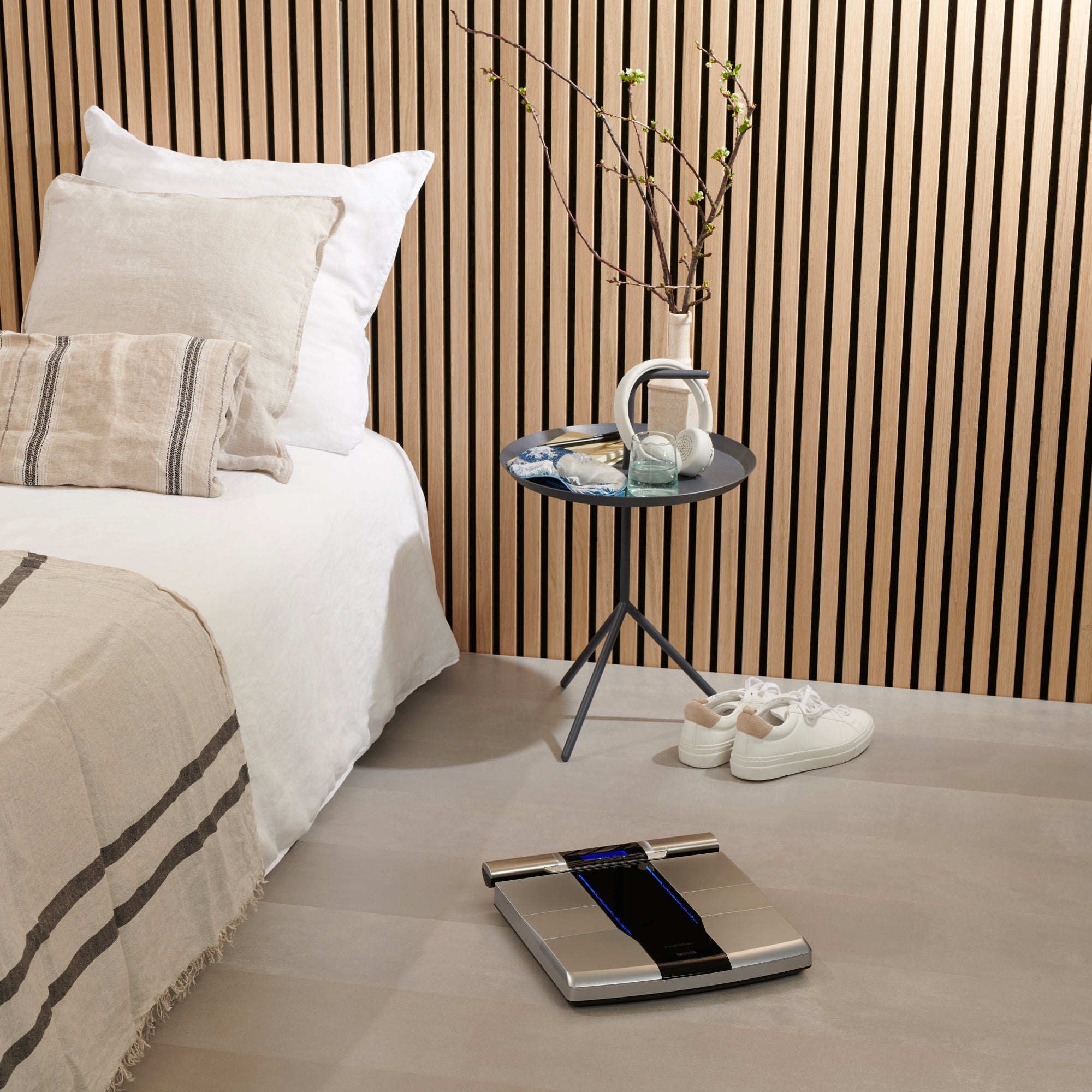 Bedroom with bed, a Tanita RD-545 Bluetooth Segmental Body Composition Monitor on the floor, and a side table with headphones.